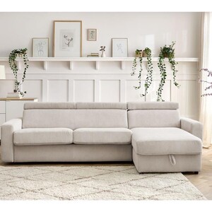 May include: A cream corduroy sectional sofa with a chaise lounge on the right. The sofa is on a cream rug. The background features a white wall, artwork, and hanging plants. The sofa is approximately 250 cm long.