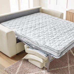 Peut inclure: Un canap&eacute;-lit beige avec un matelas d&eacute;pliable. Le matelas est blanc avec un motif matelass&eacute; et un cadre en m&eacute;tal argent&eacute;. Le canap&eacute; a un dossier gris et des accoudoirs en velours c&ocirc;tel&eacute; beige. Des oreillers sont empil&eacute;s &agrave; la base du lit.