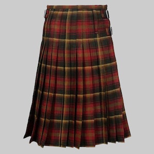 Op de afbeelding: Een traditionele kilt in een rood, zwart en goud geruit patroon. De geplooide rok heeft een klassiek ontwerp met gespsluitingen in de taille. De kilt is gemaakt van een geweven stof.