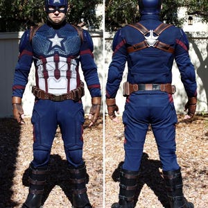 May include: A full-body Captain America costume. The costume is primarily navy blue with red and white accents. It includes a helmet with the letter "A", a star on the chest, and brown leather-like straps and gloves. The boots are black with brown straps.