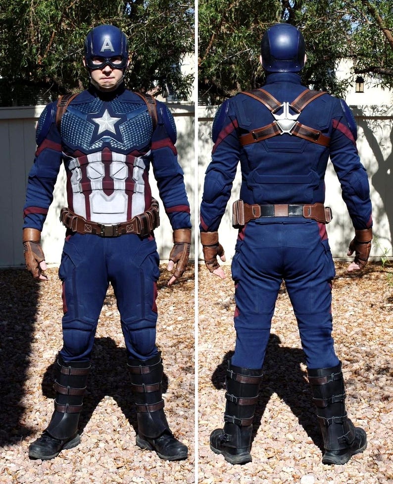 May include: A full-body Captain America costume. The costume is primarily navy blue with red and white accents. It includes a helmet with the letter "A", a star on the chest, and brown leather-like straps and gloves. The boots are black with brown straps.