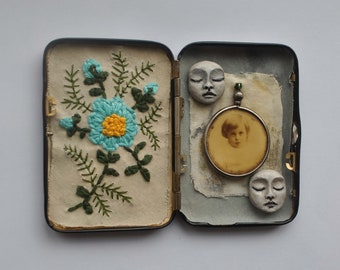 Miniature sculpture and textile assemblage inside an illustrated vintage case.