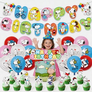 Può includere: Una scena di festa di compleanno con decorazioni a tema Snoopy. Include uno striscione con la scritta "Happy Birthday", palloncini, cupcake e una torta. Una bambina è al centro, indossa un cappello da festa e tiene in mano un cartello "Happy Birthday".