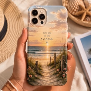 May include: A smartphone case featuring a sunset beach scene with a sandy path leading to the ocean, framed by wooden posts and small pink flowers. The text "take me to the ocean" is printed in black script above the horizon line.