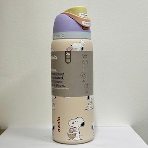 May include: A beige Owala water bottle featuring Snoopy illustrations. The bottle has a purple lid, a yellow push button, and a beige body with Snoopy designs. It is leak-proof, insulated, and has a built-in straw. The bottle is designed to keep drinks cold for 24 hours.