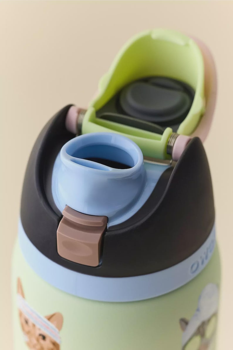 May include: A light green water bottle with a black lid, a light blue spout, and a lime green interior hinge mechanism. The bottle features a pink latch and a partial graphic of a cat wearing a headband on the lower portion of the bottle body.