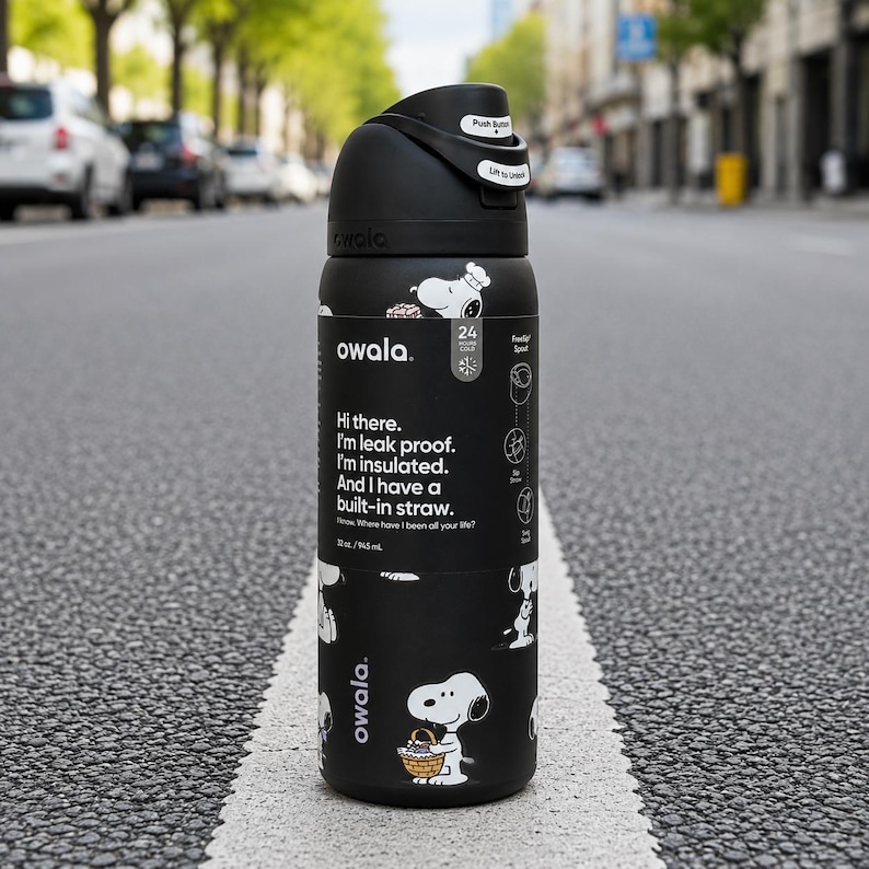 Puede incluir: Botella de agua Owala negra con ilustraciones de Snoopy y texto. La botella tiene una tapa negra con un bot&oacute;n y una pajita incorporada. La botella es de 946 ml y es a prueba de fugas y aislada.