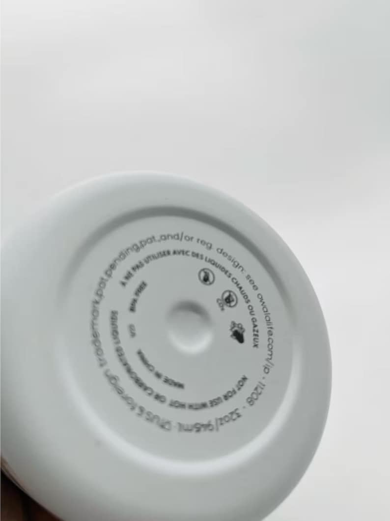 May include: White insulated water bottle base with printed text. The text includes the bottle's capacity of 32oz/946ml, and warnings about use with hot or carbonated liquids. The bottle is made in China.