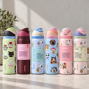 May include: Six Owala insulated water bottles with built-in straws, each featuring a unique colour scheme and graphic design. The bottles display various illustrations of cats, dogs, and Snoopy characters, along with printed text detailing product features.