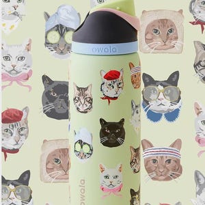 May include: A light green Owala water bottle featuring a repeating pattern of various cats in different accessories, including berets, glasses, and spa headbands. The bottle has a black, light blue, and pale pink lid with the Owala logo printed.