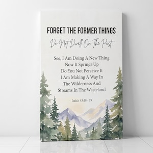 May include: A rectangular canvas wall art piece featuring a watercolor landscape of green pine trees and purple mountains at the base. The text reads: Forget the former things, Do not dwell on the past, See, I am doing a new thing, Isaiah 43:18-19.