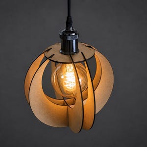 Könnte beinhalten: Eine Pendelleuchte mit einer kugelförmigen Käfigstruktur aus hellen Holzpaneelen. Die Leuchte enthält eine zentrale, klare Edison-Glühbirne mit sichtbarem glühendem Glühfaden, die an einem schwarzen Kabel und einer metallischen Fassung aufgehängt ist.