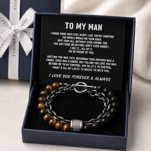 May include: A two-strand bracelet with tiger eye and black onyx beads, presented in a navy blue gift box. The box contains a card with the text "TO MY MAN" and a heartfelt message. The bracelet features a silver-tone clasp.