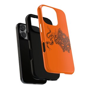 May include: An orange phone case featuring a black graphic of a detailed creature. The case is layered over a black phone and a black inner case. The phone has two camera lenses.
