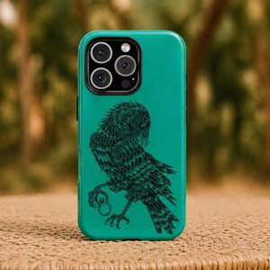 May include: Teal phone case with a black owl illustration. The owl is depicted with intricate detail, holding a ring in its talons. The case has a glossy finish and a camera module with three lenses.