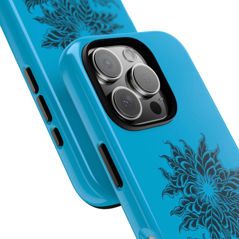 May include: Close-up of two turquoise phone cases. The cases feature a black floral design and a black camera lens protector. The phone cases are made of a smooth, glossy material. The cases are designed to fit a smartphone.