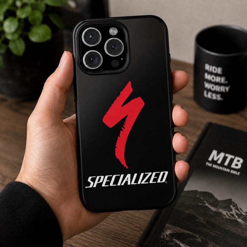 Op de afbeelding: Zwarte telefoonhoes met het rode Specialized-logo. Het logo is een gestileerde bliksemschicht boven het woord "SPECIALIZED" in witte, schreefloze letters. De hoes heeft een glanzende afwerking en is ontworpen voor een smartphone.