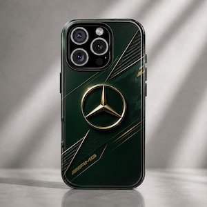 May include: A dark green phone case with a gold Mercedes-Benz logo and gold accent lines. The case has a black border and the letters "AMG" are visible in the lower right corner.