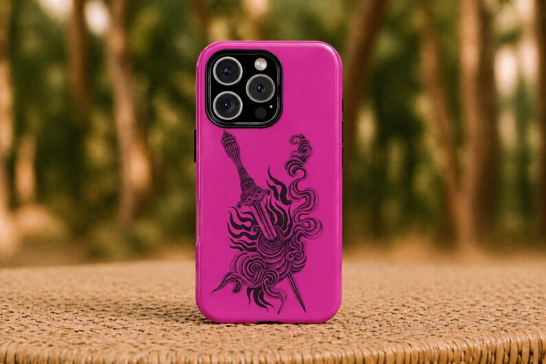May include: A magenta phone case with a black illustration of a sword and flame-like swirls. The case has a glossy finish and a camera module with three lenses. The phone case is resting on a woven surface.