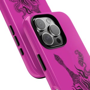 May include: Bright pink phone case with a black decorative design. The case has a black camera lens protector and black side buttons. The design appears to be a stylized illustration of a tower and smoke.
