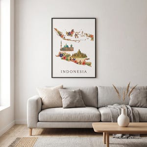 以下が含まれることがあります： インドネシアの地図が描かれた額装されたウォールアートプリント。カラフルな花柄、モスク、寺院のイラストで装飾されています。白い長方形のポスターの下部には、黒い大文字で「INDONESIA」という文字が印刷されています。