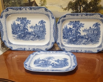 Tres bandejas antiguas azules y blancas de tres tamaños diferentes: una de 26 cm de largo por 20 cm de ancho, una mediana de 31 cm de largo por 24 cm de ancho y una extragrande de 36 cm de largo por 28 cm de ancho.