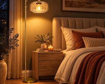 May include: A tall, gold-toned metal floor lamp with an arched neck and a clear, faceted glass shade. The lamp features a circular base and emits a warm, glowing light, illuminating the surrounding space with a soft, ambient radiance.