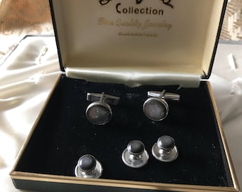 May include: A black velvet box with a gold trim containing a set of cufflinks and studs. The box has a label that reads "Designers Collection Fine Quality Jewelry Guaranteed".
