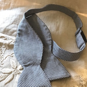 May include: A black and white patterned bow tie with a white background and black geometric shapes.