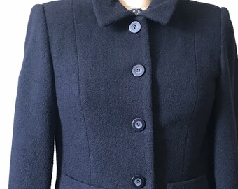 May include: A black cropped blazer with a collar and four buttons. The blazer is made of a textured fabric.
