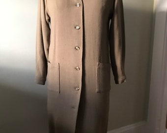 May include: A long-sleeved, button-up, brown dress with two pockets. The dress is made of a soft, textured fabric.