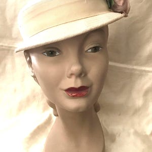 May include: A white hat with a wide brim and a pink flower accent. The hat is made of a soft, textured fabric.