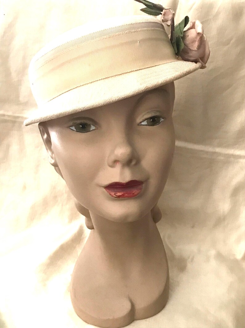 May include: A white hat with a wide brim and a pink flower accent. The hat is made of a soft, textured fabric.