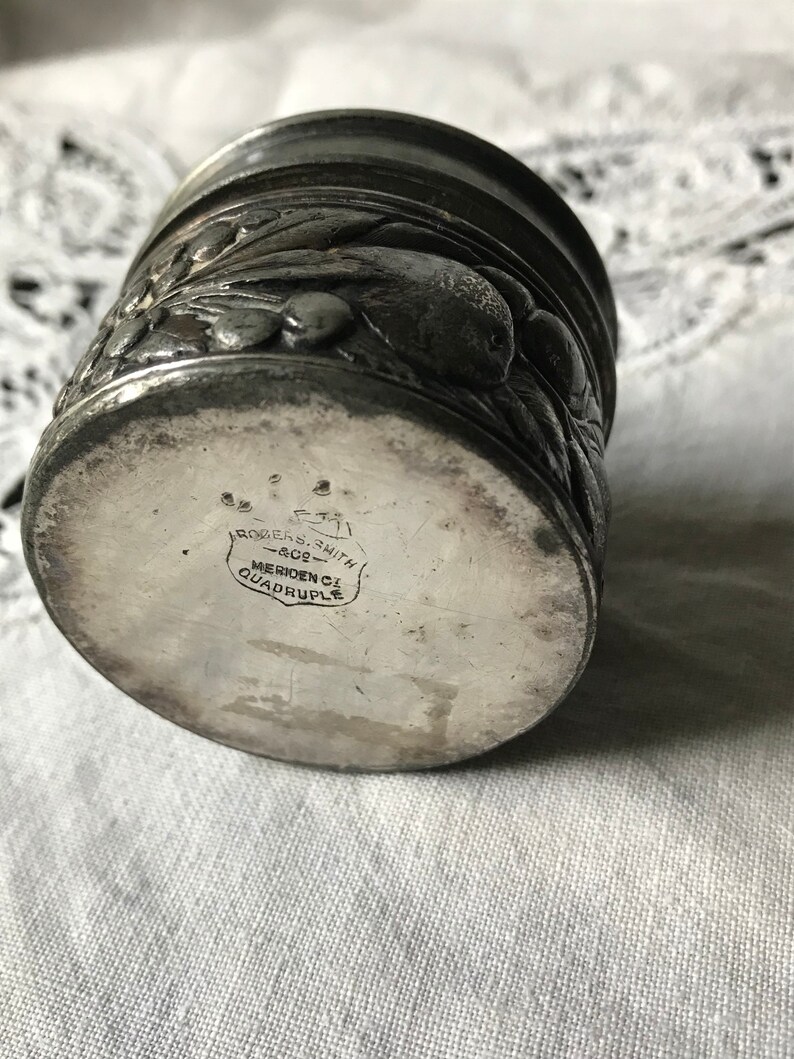 May include: Silver plated cup with an embossed floral design. The bottom of the cup is marked "Rogers & Smith, Meriden, CT, Quadruple".