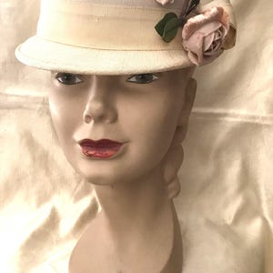 May include: A white straw hat with a wide brim and a pink fabric rose with green leaves on the side.