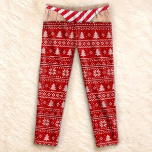 May include: Red leggings featuring a white fair isle pattern of Christmas trees and snowflakes. The waistband area displays a printed graphic of skin-toned fabric with a red and white diagonal striped thong design visible at the top edge.