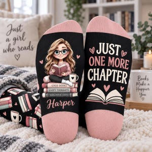 May include: A pair of black socks with pink cuffs. One sock features a cartoon girl with glasses reading a book atop a stack of books labeled Good Books, Happy Thoughts, Brighter Days, and the name Harper. The other sock says Just One More Chapter.