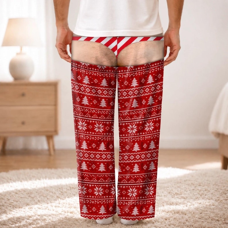 May include: Red and white lounge trousers featuring a festive holiday pattern of Christmas trees and snowflakes. The design includes a printed graphic of a red and white striped thong at the waistline, creating an illusion of exposed skin.