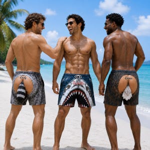 May include: Three pairs of novelty swim trunks. The left pair features a gray fur pattern with a raccoon tail and the name Emily. The center pair shows a shark face with the name Isabella. The right pair has a brown fur pattern with a tail and the name Emma.
