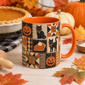 May include: A ceramic mug with an orange interior and handle, featuring a patchwork design of black cats, jack-o'-lanterns, pumpkin pie slices, and geometric quilt patterns in shades of orange, black, brown, and green on a cream background.