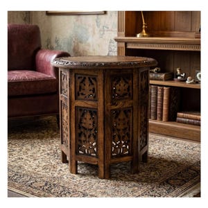 May include: A round wooden side table featuring intricate hand-carved floral patterns on its top surface and six vertical panels. The table has a dark brown finish and a sturdy base with multiple legs, showcasing detailed craftsmanship throughout.