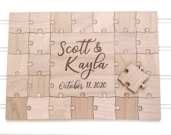 May include: Wooden puzzle guest book with the names "Scott & Kayla" and the date "October 17, 2020" engraved in a decorative font. The puzzle is made of light-colored wood and includes a loose puzzle piece.