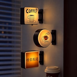 Könnte beinhalten: Drei wandmontierte Leuchtschilder mit schwarzem Rahmen. Das obere quadratische Schild zeigt eine Kaffeetasse und den Text COFFEE?. Das mittlere runde Schild zeigt eine Katze mit einer Kaffeetasse und den Text COFFEE. Das untere quadratische Schild zeigt chinesischen Text.