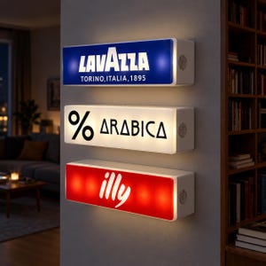 May include: Three rectangular wall-mounted light boxes stacked vertically. The top blue sign reads LAVAZZA TORINO, ITALIA, 1895. The middle white sign features a percent symbol and the word ARABICA. The bottom red sign displays the white text illy.