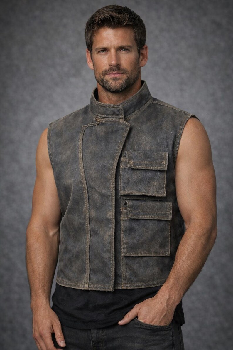 May include: A sleeveless vest in a distressed charcoal gray finish featuring a high collar, an asymmetrical front closure, and two stacked rectangular cargo pockets on the left side. The garment has visible stitching and a weathered, textured appearance.