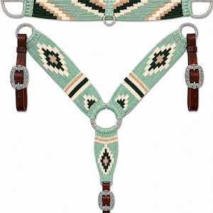 May include: A horse cinch and breast collar set featuring a woven geometric pattern in mint green, dark green, and tan. The set includes silver-toned metal hardware, buckles, and brown leather straps with ornate silver-toned buckle accents.