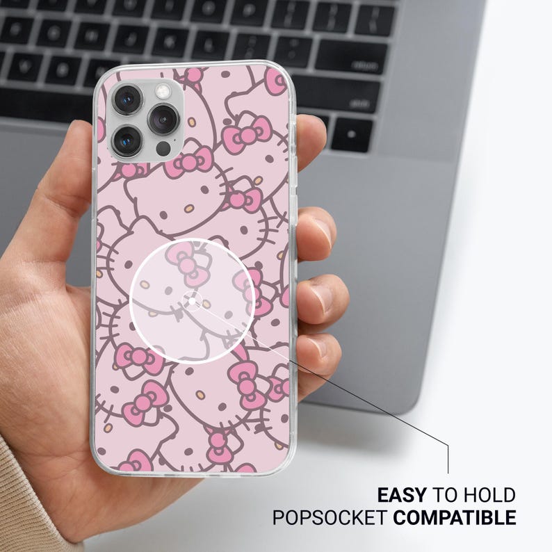 Puede incluir: Una funda transparente para tel&eacute;fono con un dise&ntilde;o rosa de Hello Kitty y lazos. La funda se sostiene en una mano y tiene un PopSocket. El texto en la imagen dice "EASY TO HOLD POPSOCKET COMPATIBLE".