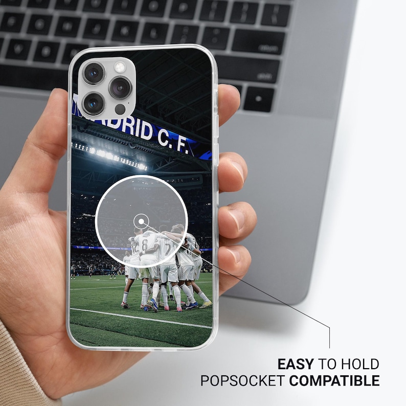 Puede incluir: Funda transparente para tel&eacute;fono con un equipo de f&uacute;tbol con uniformes blancos en un campo verde. La funda tiene el texto "MADRID C.F." y las palabras "EASY TO HOLD POPSOCKET COMPATIBLE".