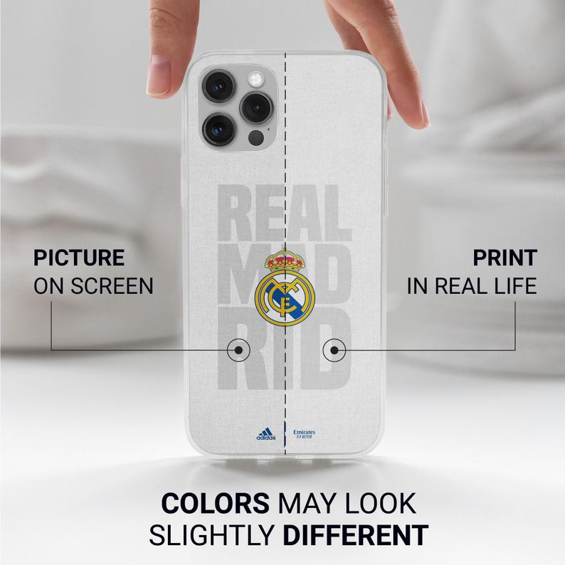 Puede incluir: Una funda blanca para tel&eacute;fono con el logotipo y el nombre del equipo del Real Madrid en gris. La funda tiene un dise&ntilde;o claro y protector. El texto "COLORS MAY LOOK SLIGHTLY DIFFERENT" est&aacute; impreso en la parte inferior.