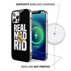 Puede incluir: Funda de tel&eacute;fono negra con texto "REAL MAD RID" y un logotipo del equipo. La pantalla del tel&eacute;fono muestra un s&iacute;mbolo de carga. Tambi&eacute;n se ve un cargador inal&aacute;mbrico blanco. El texto de la imagen dice "SUPPORTS WIRELESS CHARGING" y "SIDES ARE NOT PRINTED".